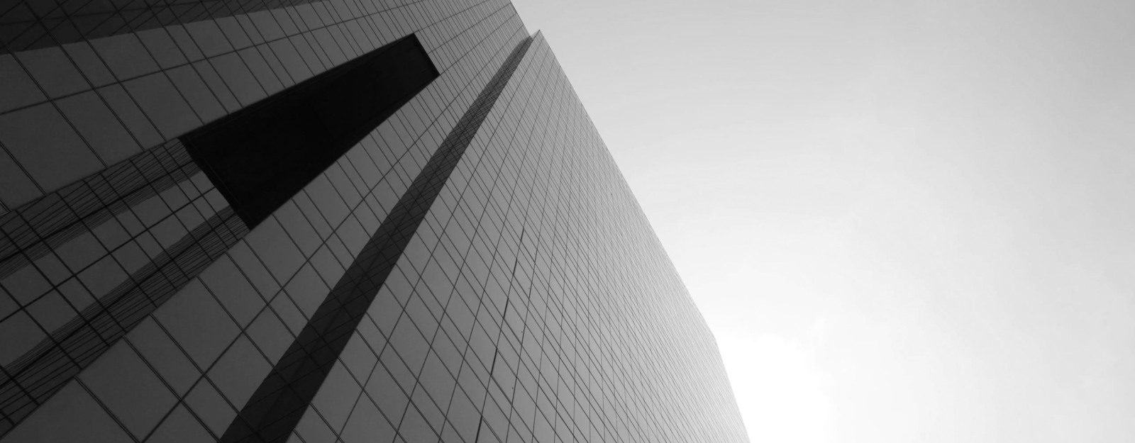 CloudMasonry Salesforce Consulting - Background Image - Tall glass skyscraper against cloudy sky.