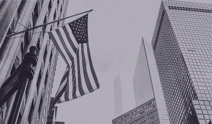 CloudMasonry Salesforce Consulting - Background Image - American flag waves among city skyscrapers.