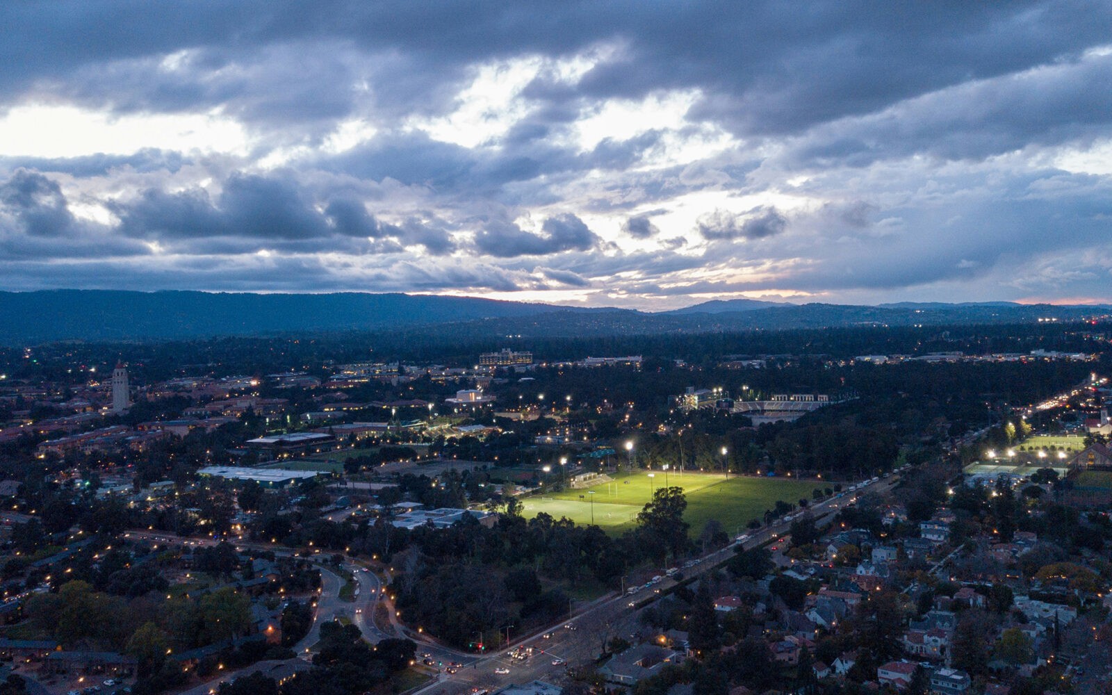 bg-paloalto2 CloudMasonry - California Based Salesforce Consulting - Palo Alto Office Landing Page Image - Cityscape at dusk with illuminated sports fields.